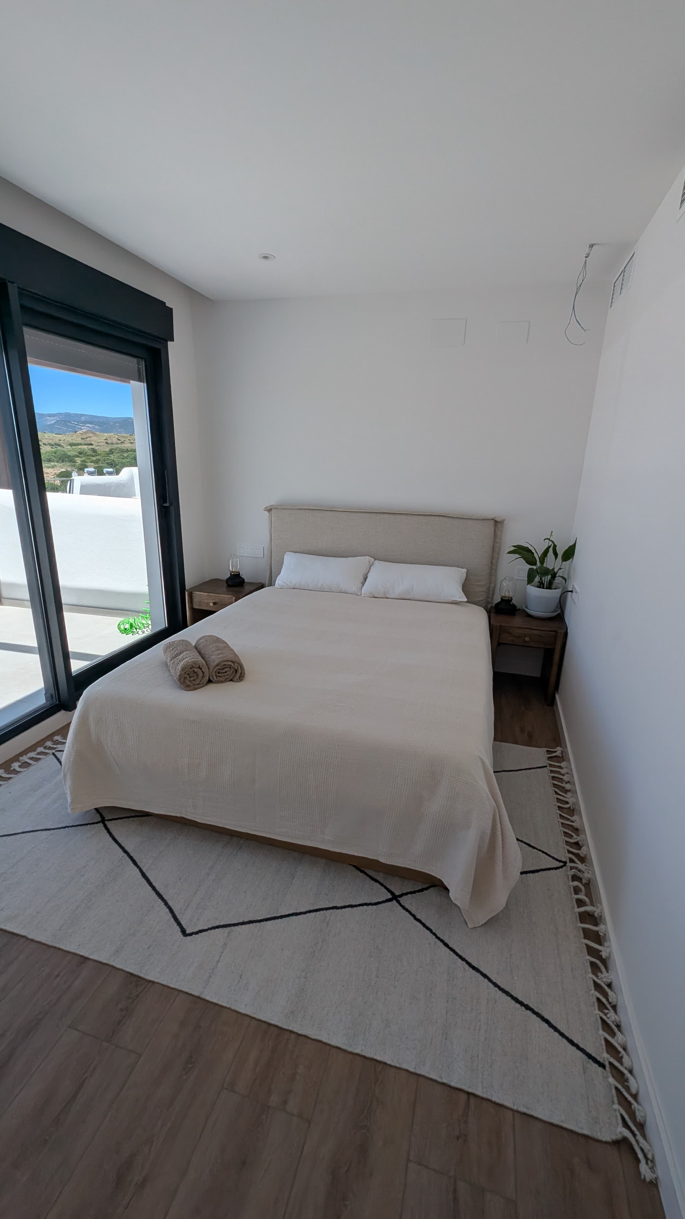Main bedroom with double bed, linen headboard and Berber rug