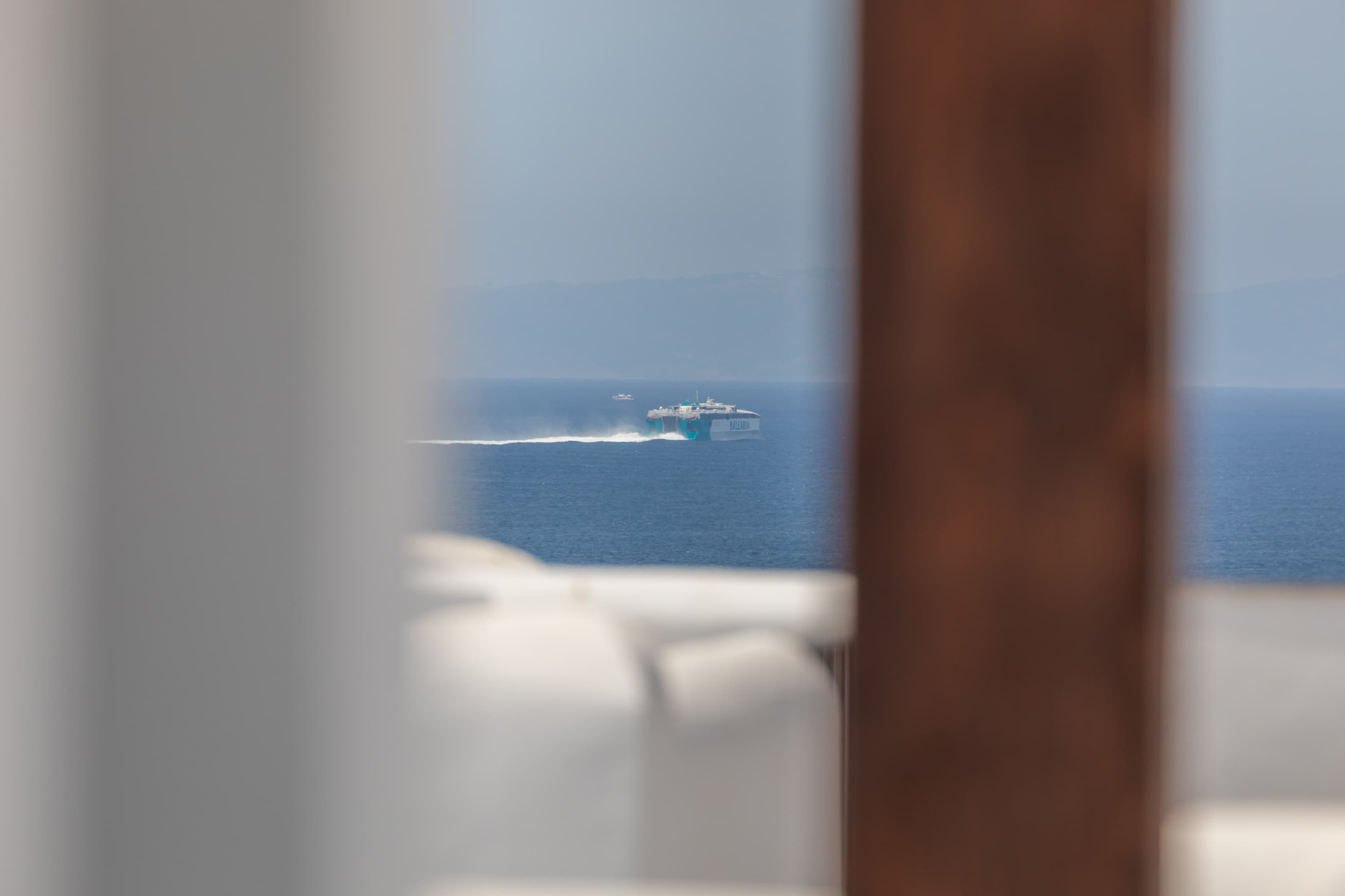 Fast ferry crossing the Strait of Gibraltar to Morocco, framed through the upstairs pergola
